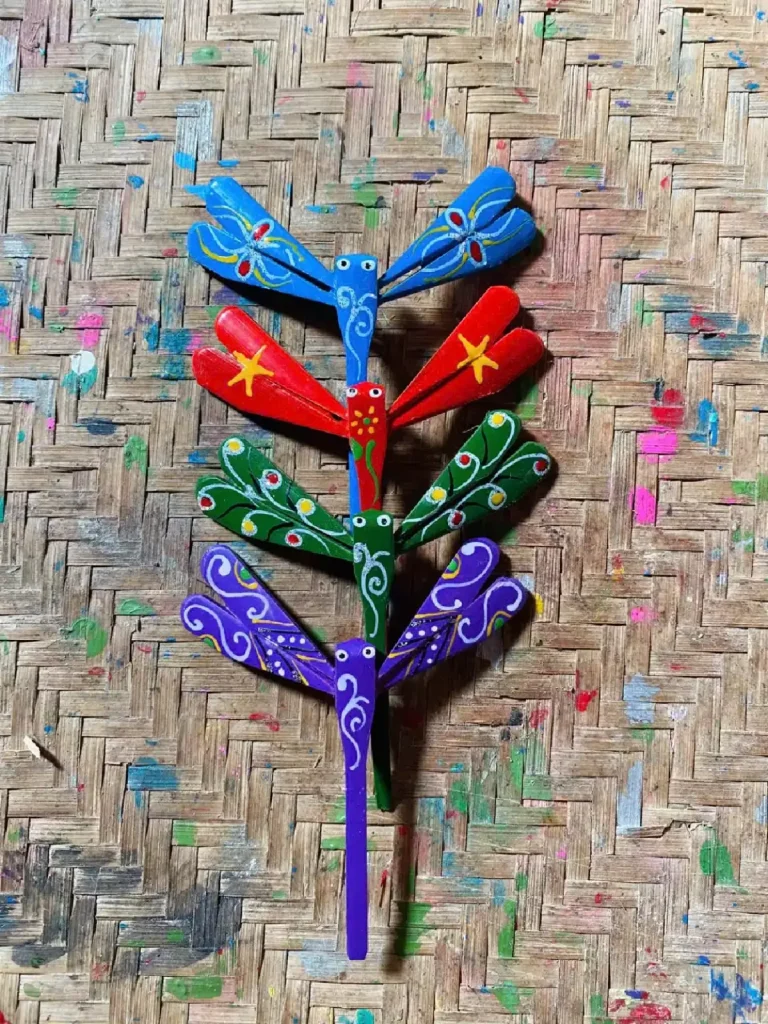 Four painted bamboo dragonflies on a woven bamboo mat